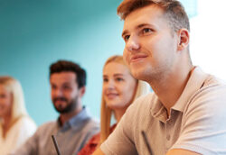 Student listening to tutor whilst taking notes